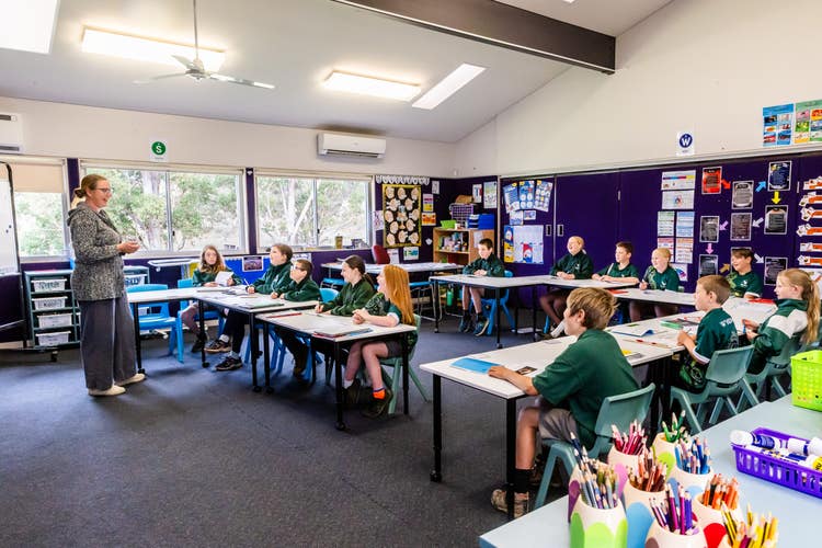 classroom with students sitting at desk with teacher at the front of the room