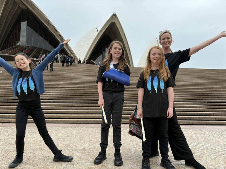3 students with teacher holding recorders outside the Sydney Opera House