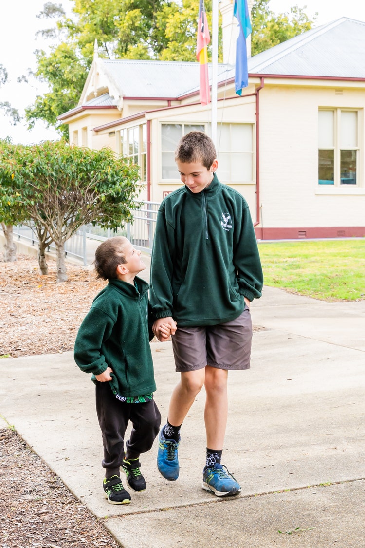 Year 6 student walking with kindy student
