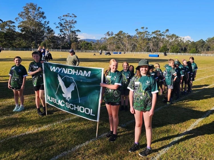 Students at athletics carnival marching with school banner