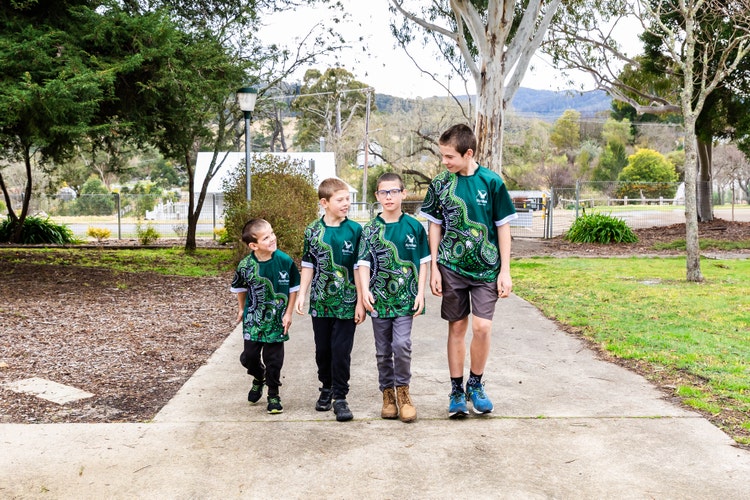 4 students walking towards camera up the path looking at each other.
