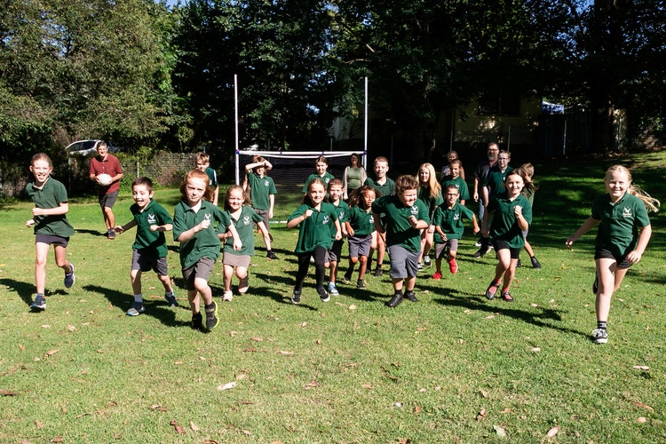 All age students running towards camera on oval