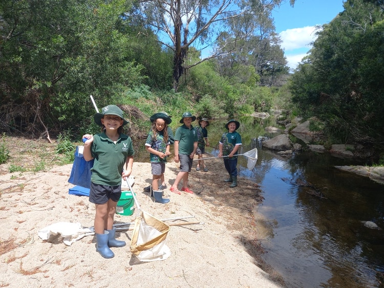 students standing on the sandy banks of the local creek