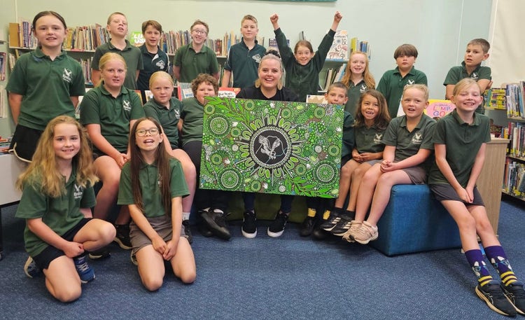 Students sitting with artist who designed the school indigenous artwork